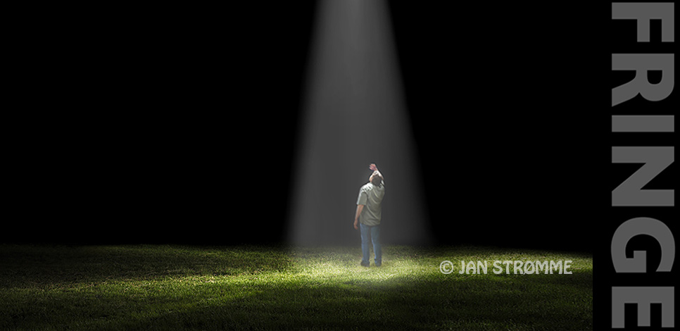 Man standing in a field looking up into a spotlight