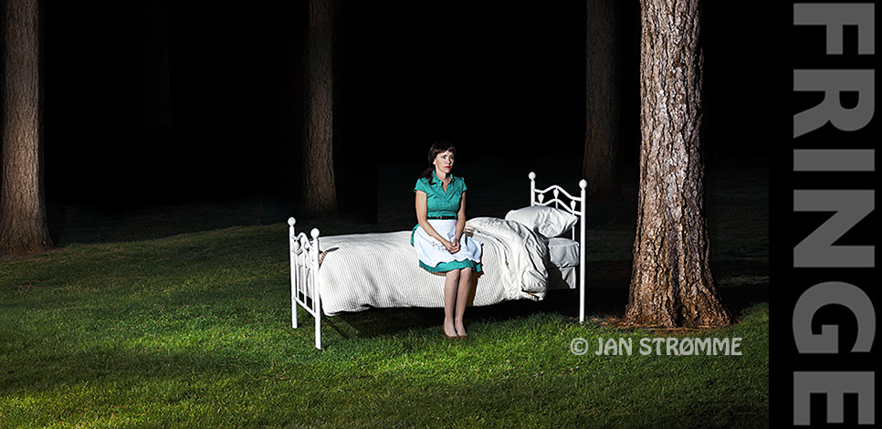 Surreal image of a middle-aged woman sitting on a bed in a forest at night